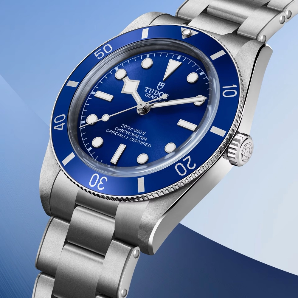 Tudor Black Bay 54 dalış kol saati, parlak mavi kadranı, dönen mavi bezelindeki beyaz dalış işaretleri ve paslanmaz çelik kasası ve bileziğiyle, 200 metre su geçirmezlik özelliğini belirten yazısıyla lüks ve fonksiyonel tasarımını vurguluyor.