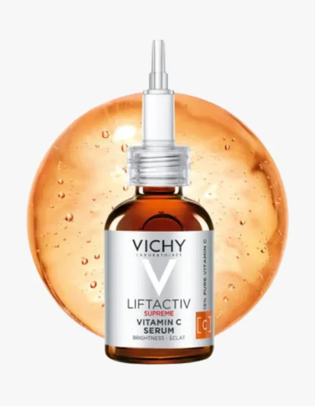 Beyaz damlalıklı kapağa sahip kahverengi Vichy Liftactiv Supreme C Vitamini Serumu şişesi, ürünün cildi aydınlatma ve parlaklık verme özelliğini vurgulayan parlak turuncu bir sıvı damlasının önünde duruyor.