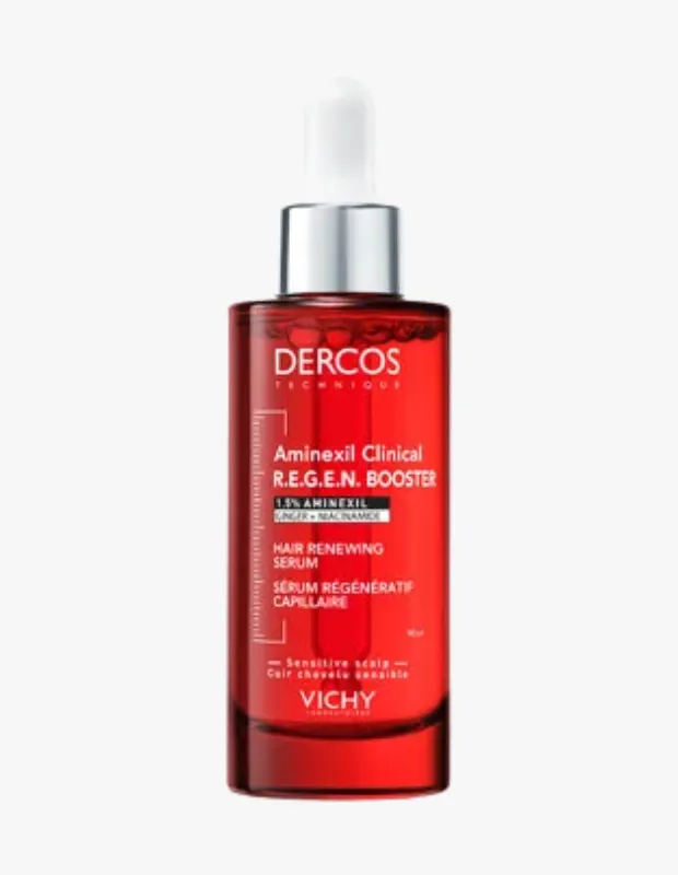 Şeffaf kırmızı renkli cam şişede, beyaz damlalıklı kapağı ve metalik gümüş halkası olan Vichy Dercos Aminexil Clinical R.E.G.E.N. Booster saç serumu, üzerinde 1.5% Aminexil, zencefil ve niasinamid ile saç yenileyici etkisini belirten etiketle görülüyor.