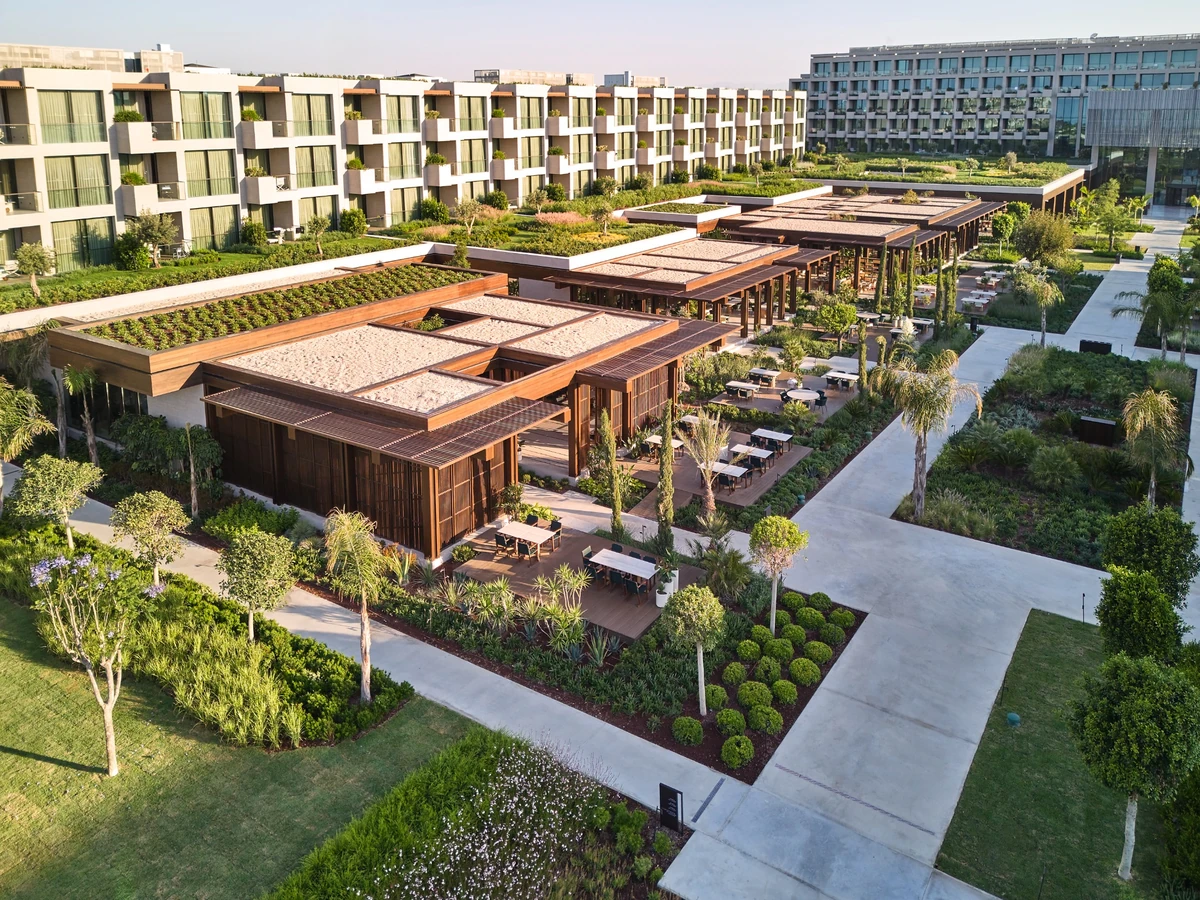 Kundu Antalya'daki modern bir otelin kuşbakışı genel görünümü, yemyeşil peyzajlı bahçelerle çevrili şık dış mekan restoran ve dinlenme alanları ile çok katlı binalarını gösteriyor.