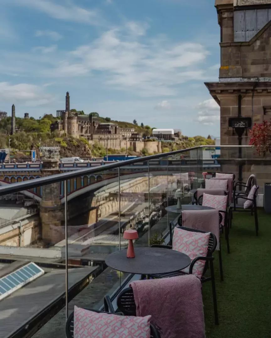 Market Street Hotel'in canlı ve şık çatı katı terası, pembe minderlerle süslenmiş oturma alanları ve Calton Tepesi'ndeki tarihi yapılarla şehrin köprüsünün eşsiz birleşimini sunan büyüleyici Edinburgh manzarasına nazır.