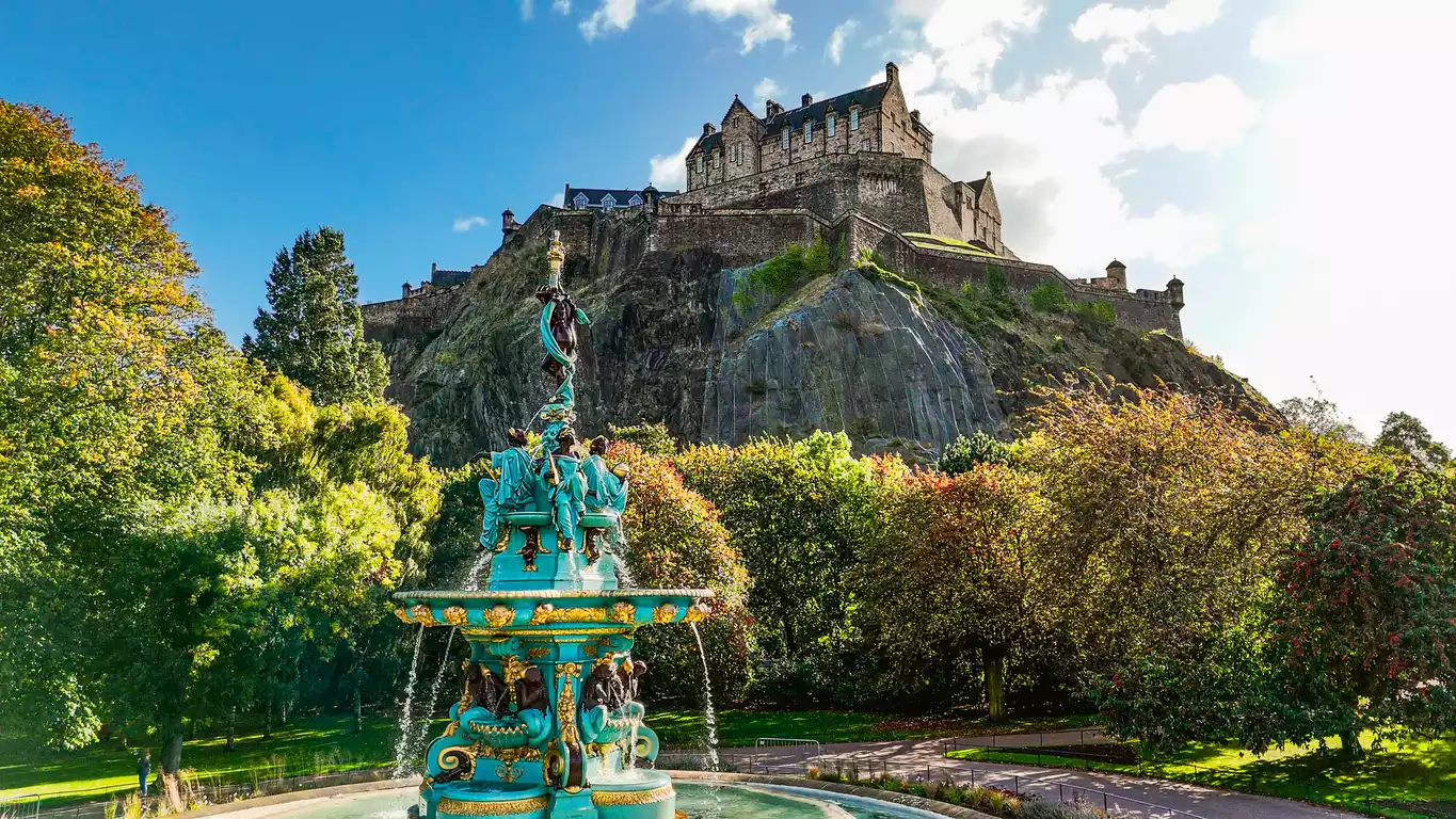 Princes Street Gardens'ın yemyeşil alanları ve sonbahar renklerine bürünmüş ağaçları arasında, süslü turkuaz Ross Çeşmesi'nin berrak suları keyifli bir melodiyle akarken, tarihi Edinburgh Kalesi kayalık bir tepe üzerinde tüm ihtişamıyla göğe uzanıyor.