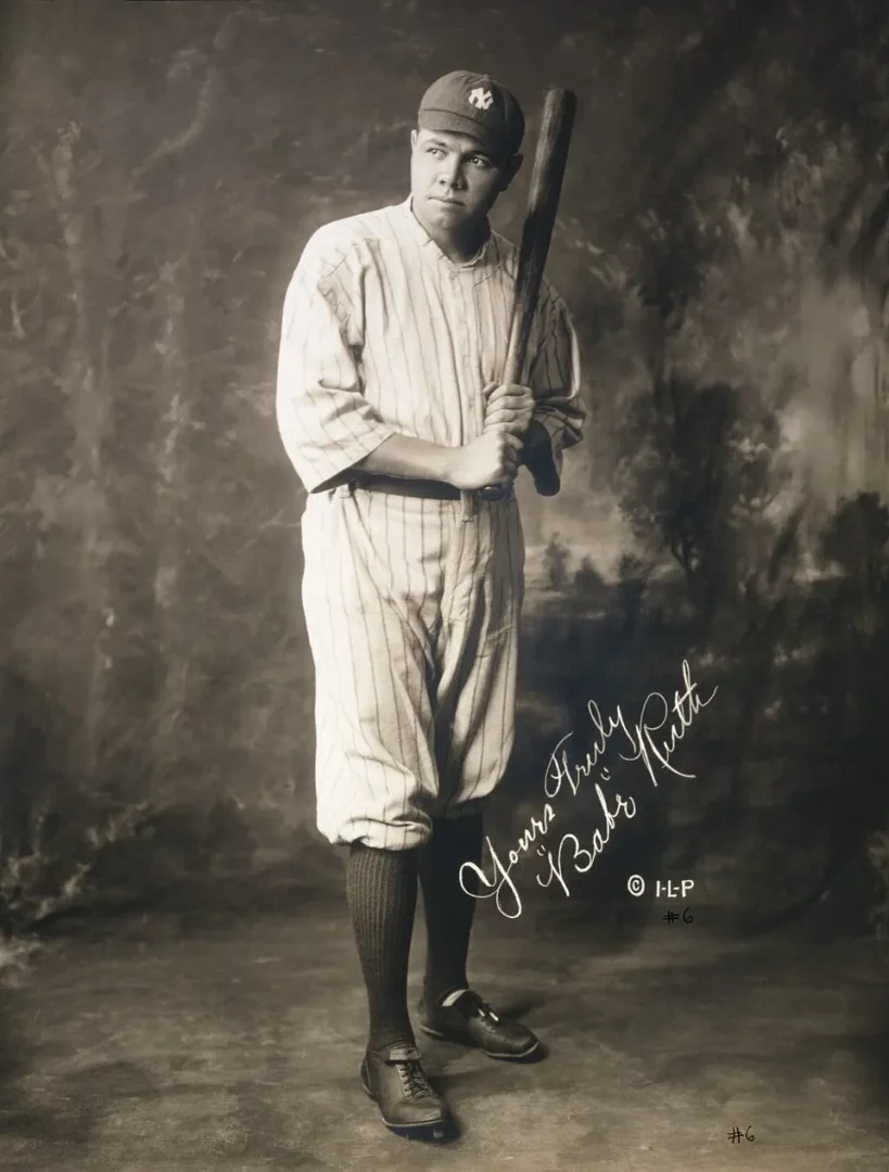 Beyzbol tarihinin efsanevi ismi Babe Ruth'un, New York Yankees'in ikonik çizgili forması ve omzunda beysbol sopasıyla poz verdiği, imzalı ve nostaljik bir hava taşıyan bu siyah beyaz portre fotoğrafı, onun sahadaki karizmasını ve döneminin ruhunu yansıtmaktadır.