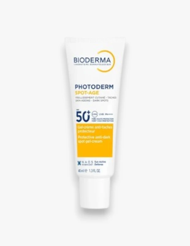 Dikey olarak duran, üzerinde Bioderma logosu, Photoderm SPOT-AGE ibaresi ve SPF50+ güneş koruma faktörü açıkça belirtilen, sarı vurgulu beyaz bir leke karşıtı jel-krem tüpü, ciltteki koyu lekeler ve yaşlanma belirtilerine karşı etkili koruma sağladığını gösteriyor.