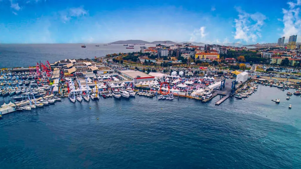 Ataköy Marina'daki Bosphorus Boat Show Deniz Fuarı'nın geniş açılı hava fotoğrafında, fuar için özel olarak düzenlenen iskelelere bağlı, lüks motor yatlar ve yelkenliler dahil yüzlerce teknenin yanı sıra, kalabalık kıyı şeridinde etkinlik çadırları ve şehir manzarası dikkat çekiyor.