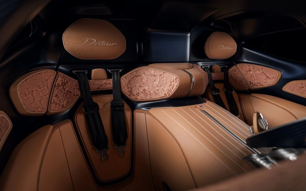 Bugatti Destrier hiper otomobilinin zengin iç tasarımı, üzerinde Destrier yazısı bulunan kahverengi deri koltuklar, bronz rengi dokulu yan paneller ve sportif siyah yarış kemerleriyle lüks ve performansı bir araya getiriyor.