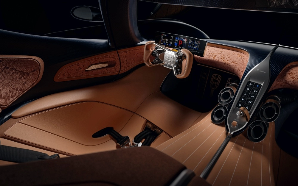 Bugatti Derstrier hiper otomobilin özgün iç mekan tasarımı, kahverengi deri ve nubuk kaplamalı geniş yüzeyleri, özel dokulu ahşap detaylarla süslenmiş gösterge paneli ve kapı içi, dijital ekranlı minimalist direksiyon simidi ile eşsiz bir lüks sunuyor.