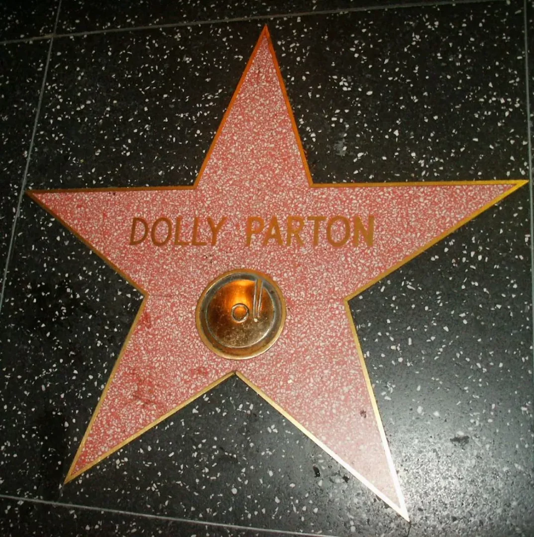 Hollywood Ünlüler Kaldırımı'nda siyah benekli bir zemine gömülü, altın kenarlı ve pembe, taş dokulu yıldız plaketin üzerinde Dolly Parton adı ile müzik sanatı kategorisini belirten pirinç bir disk belirgin bir şekilde yer alıyor.
