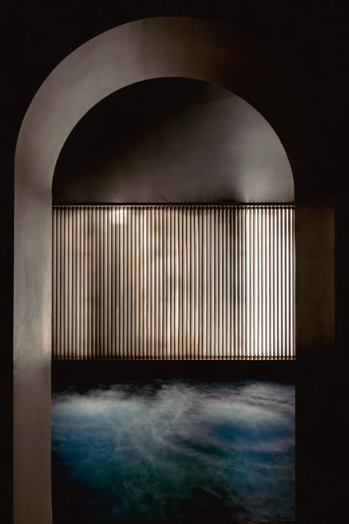 Koyu tonlarda kemerli bir nişin altındaki, buharı yükselen koyu mavi kapalı havuz, Experimental Marais beş yıldızlı otelinin sunduğu lüks ve rahatlatıcı spa alanının gizemli atmosferini yansıtıyor.