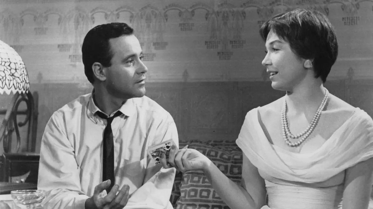 Billy Wilder'ın The Apartment filminin siyah beyaz bir sahnesinde, beyaz gömlekli ve kravatlı Jack Lemmon ile inci kolyeli, zarif elbiseli Shirley MacLaine, samimi bir garsoniyer ortamında karşılıklı oturmuş, adam elinde maça kızı kartını tutarken kadın ona hafifçe gülümseyerek bakıyor.
