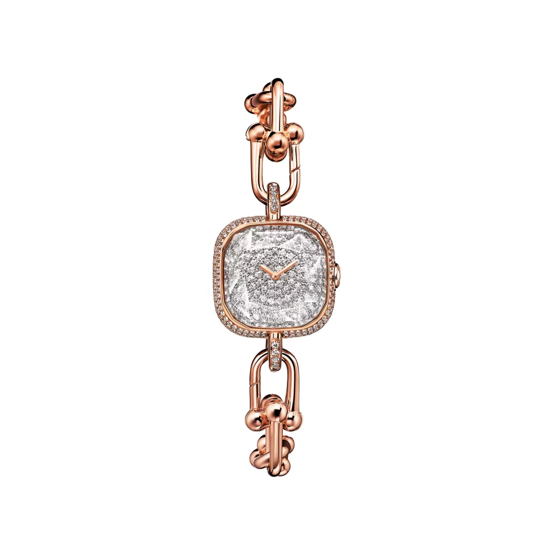 Tiffany & Co.'nun HardWear koleksiyonundan, roze altın renginde, zincir bağlantılı ve top detaylı bileziğe sahip, köşeleri yuvarlak kare kasası ve kadranı pırlantalarla tamamen bezeli lüks bir kol saati.