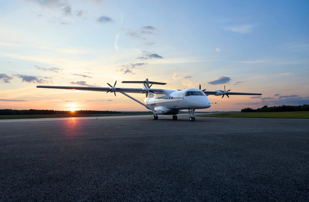 Geniş kanatlı ve dört pervaneli, beyaz renkli Heart Aerospace elektrikli uçak, gün batımının sıcak turuncu tonlarıyla aydınlanan pistte konumlanmış, dünyanın en büyük elektrikli uçağı özelliğini taşıyor.