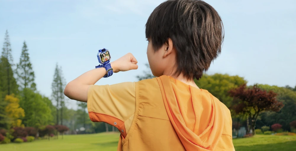 Çocuğun sırtı dönük olduğu ve açık havada durduğu bir karede, sol bileğinde mavi renkli Huawei Watch Kids X1 akıllı saatinin ekranında canlı bir video çağrısı görüntüsü belirgin şekilde görülüyor.