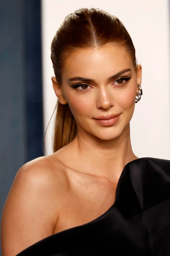 Kendall Jenner, ortadan ayrılmış, sıkıca arkaya toplanmış parlak karamel tonlarındaki saçları, sade ama şık makyajı ve omuzları açık siyah elbisesiyle esmer tenlilere yakışan modern saç renklerinden birini sergiliyor.