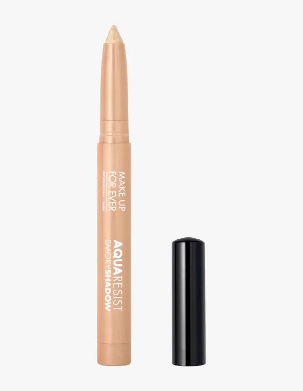Make Up For Ever Aqua Resist SmokyShadow serisinden, ucu açılmış ve kullanıma hazır durumda olan açık bej rengi bir göz kalemi, yanında siyah parlak kapağıyla beyaz bir zeminde dikey olarak konumlandırılmış.
