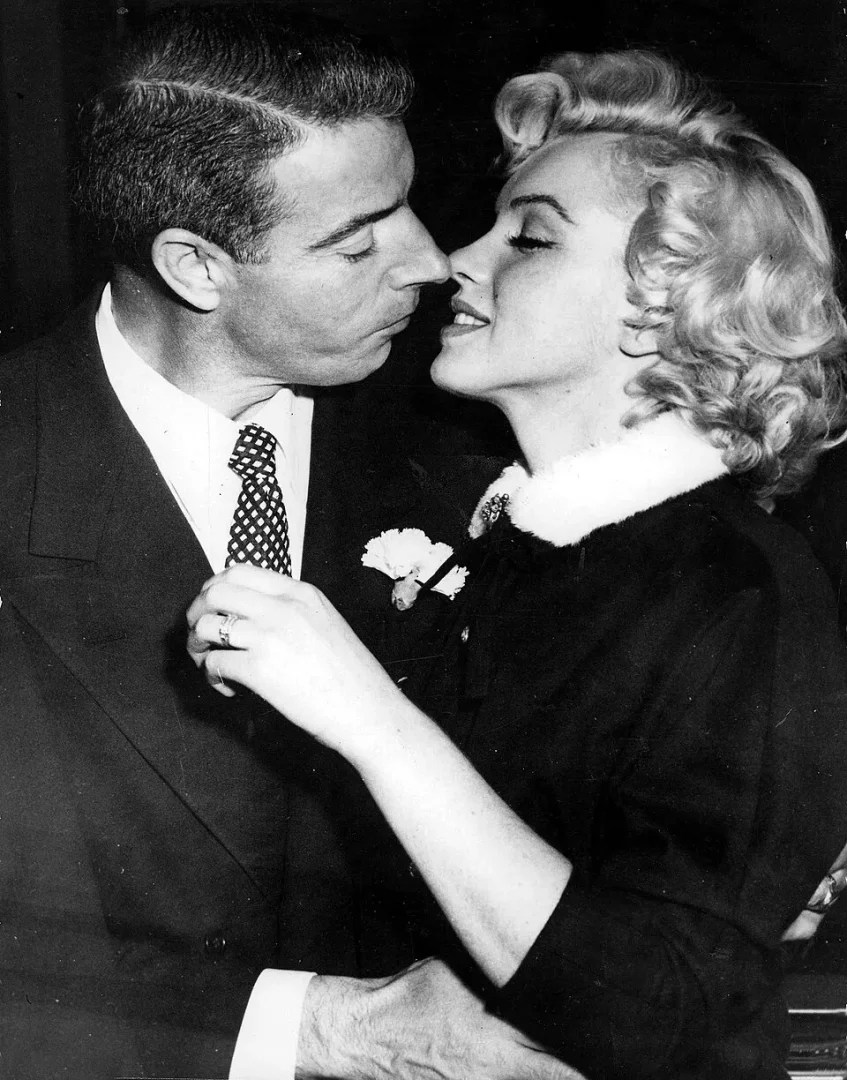 Marilyn Monroe ve eşi Joe DiMaggio'nun evlilikleri sırasında çekilmiş bu siyah beyaz fotoğrafta, birbirlerine burun buruna sevgiyle yaklaşan çiftin Monroe'nun elindeki yüzük ve DiMaggio'nun yakasındaki çiçeğin detayları romantik anı tamamlıyor.
