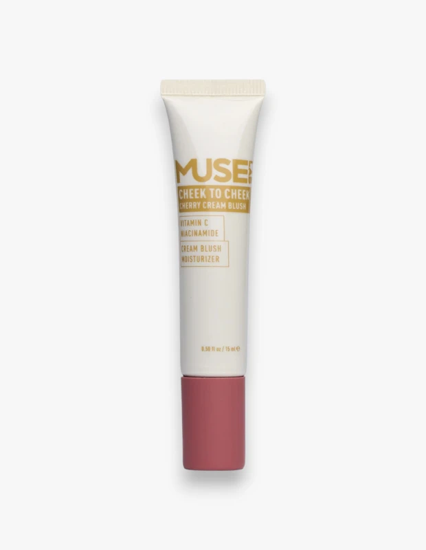 Beyaz arka plan üzerinde dikey duran, somon pembe kapağıyla dikkat çeken, üzerinde MUSE! CHEEK TO CHEEK CHERRY CREAM BLUSH ibaresi bulunan, C Vitamini ve Niasinamid içeren nemlendiricili bir krem allık tüpü detaylıca gösteriliyor.