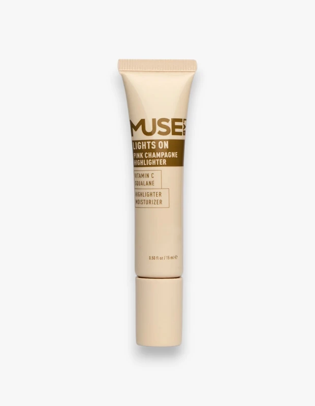 Aydınlık beyaz bir zemin üzerinde dikey duran, Muse Labs markasının Lights On Pink Champagne Highlighter adlı, C vitamini ve skualan içerikli pembe şampanya tonlarında, hem aydınlatıcı hem de nemlendirici özelliklere sahip kozmetik ürünü.