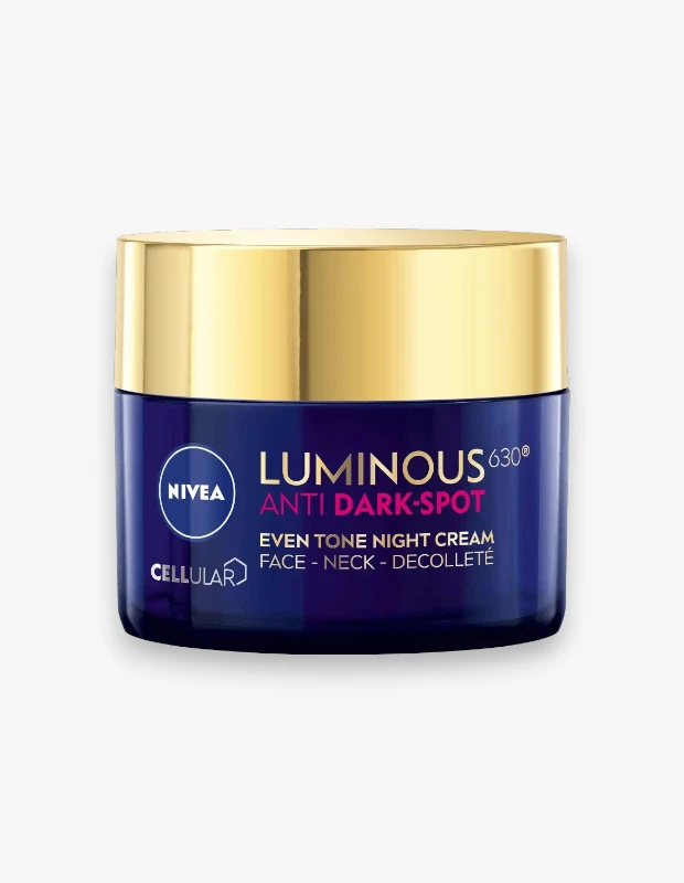 Koyu lacivert renkte, parlak altın sarısı kapaklı Nivea Luminous630 kavanozunun üzerinde Nivea logosu ve ANTI DARK-SPOT EVEN TONE NIGHT CREAM FACE - NECK - DECOLLETTE yazısı belirgin bir şekilde görülüyor, bu görsel cildin koyu leke görünümünü azaltmaya yardımcı olan bir gece kremini tanıtıyor.