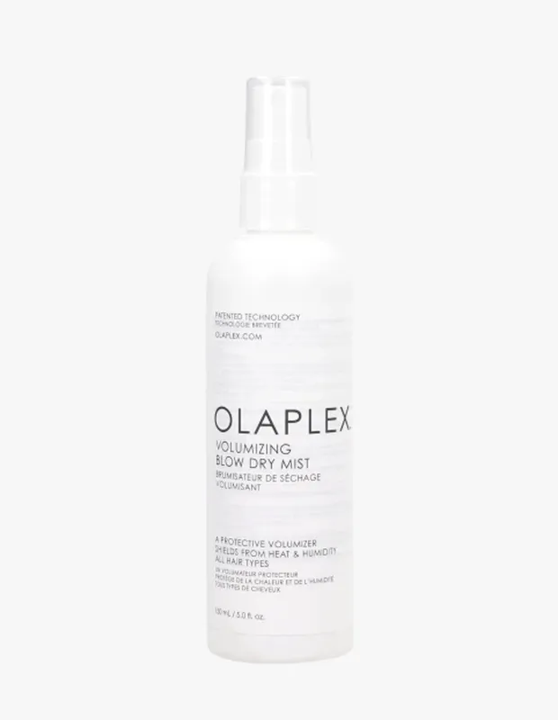 Beyaz arka plan önünde, üzerinde Olaplex markası ve Volumizing Blow Dry Mist yazan, saçlara hacim veren ve ısı ile neme karşı koruma sağlayan 150 ml'lik bir fön spreyi şişesi dik duruyor.