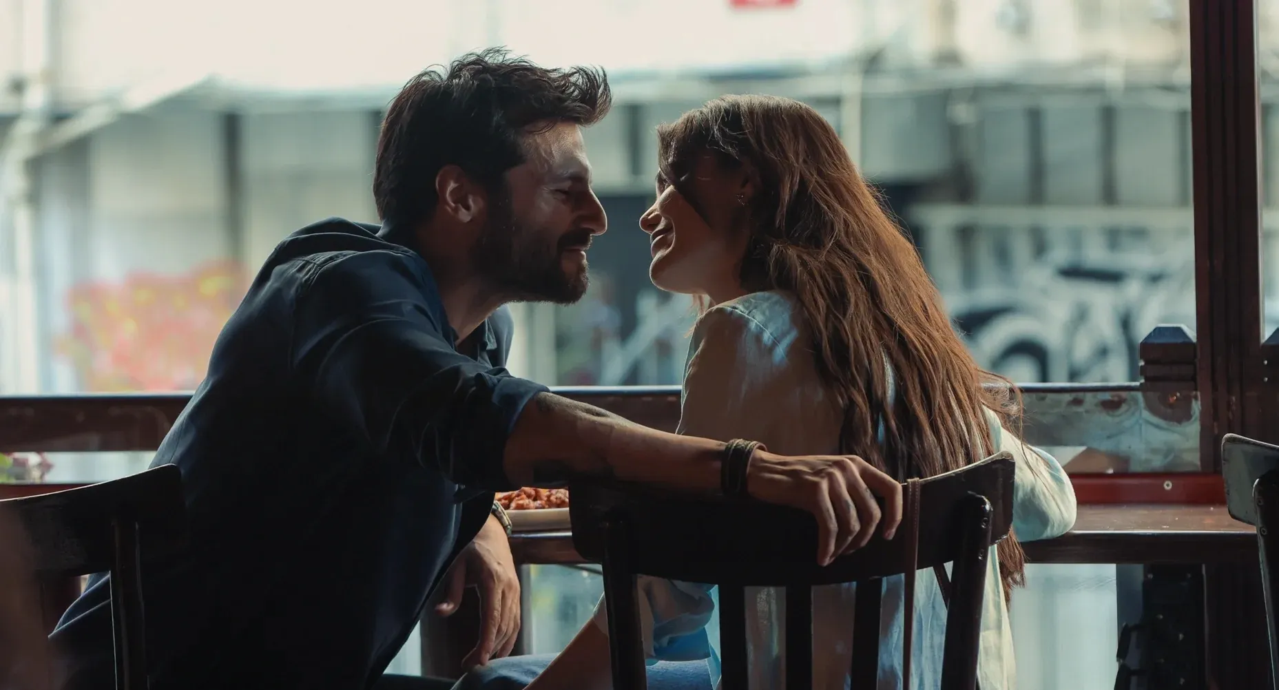 Loş ışıklı bir kafede, birbirine doğru eğilmiş, samimi ve mutlu bir ifadeyle gülümseyen, adeta fısıldayan bir çiftin sıcak anı, okuyuculara OGGUSTO'nun yeni film ve dizi önerileriyle keyifli ve romantik anlar yaşatmayı vaat ediyor.