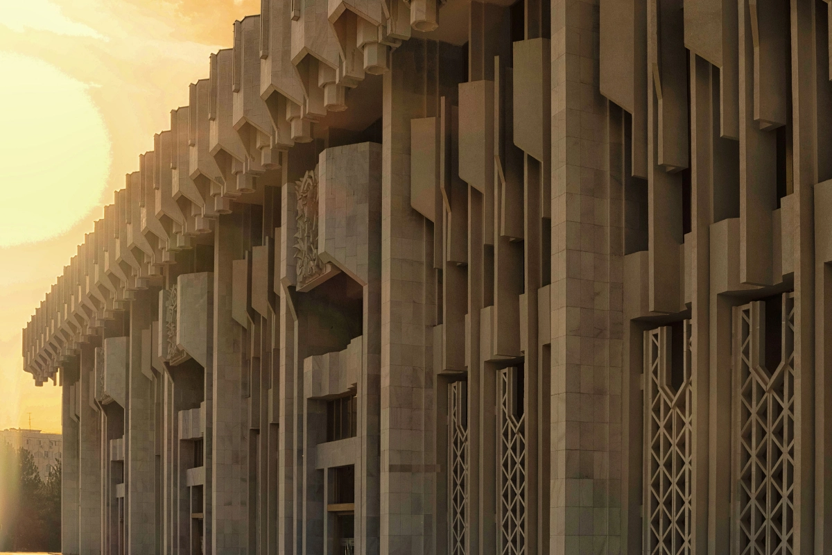 Özbekistan'ın Taşkent şehrinde yer alan ve 2026 UNESCO Dünya Mirası Listesi'ne eklenen modernist mimarinin çarpıcı bir örneği olan bu büyük yapının, geometrik desenleri, dikey hatları ve ışık oyunlarıyla dikkat çeken bej renkli cephesi gün batımında parlıyor.
