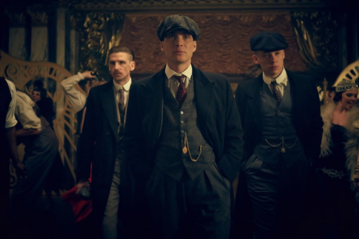 Peaky Blinders dizisinden Tommy Shelby, Arthur ve John, dönemin şık giysileri ve ikonik kasketleriyle lüks bir iç mekanda kararlı adımlarla ilerlerken, organize suç dünyasının en iyi suç ve polisiye dizileri arasındaki yerini vurguluyor.