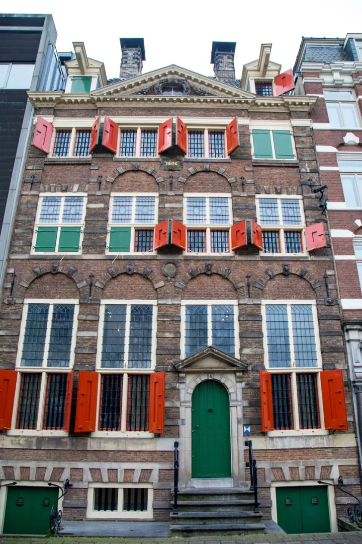 Amsterdam'da bulunan, tarihi Rembrandt Evi'nin kahverengi tuğlalı, dört katlı cephesi, üst katlarda '1606' yazısıyla birlikte açılmış turuncu-kırmızı ve kapalı yeşil ahşap kepenkli çok sayıda pencereye, zemin katta ise basamaklarla ulaşılan kemerli yeşil bir ana giriş kapısına ve demir parmaklı pencerelere sahip.