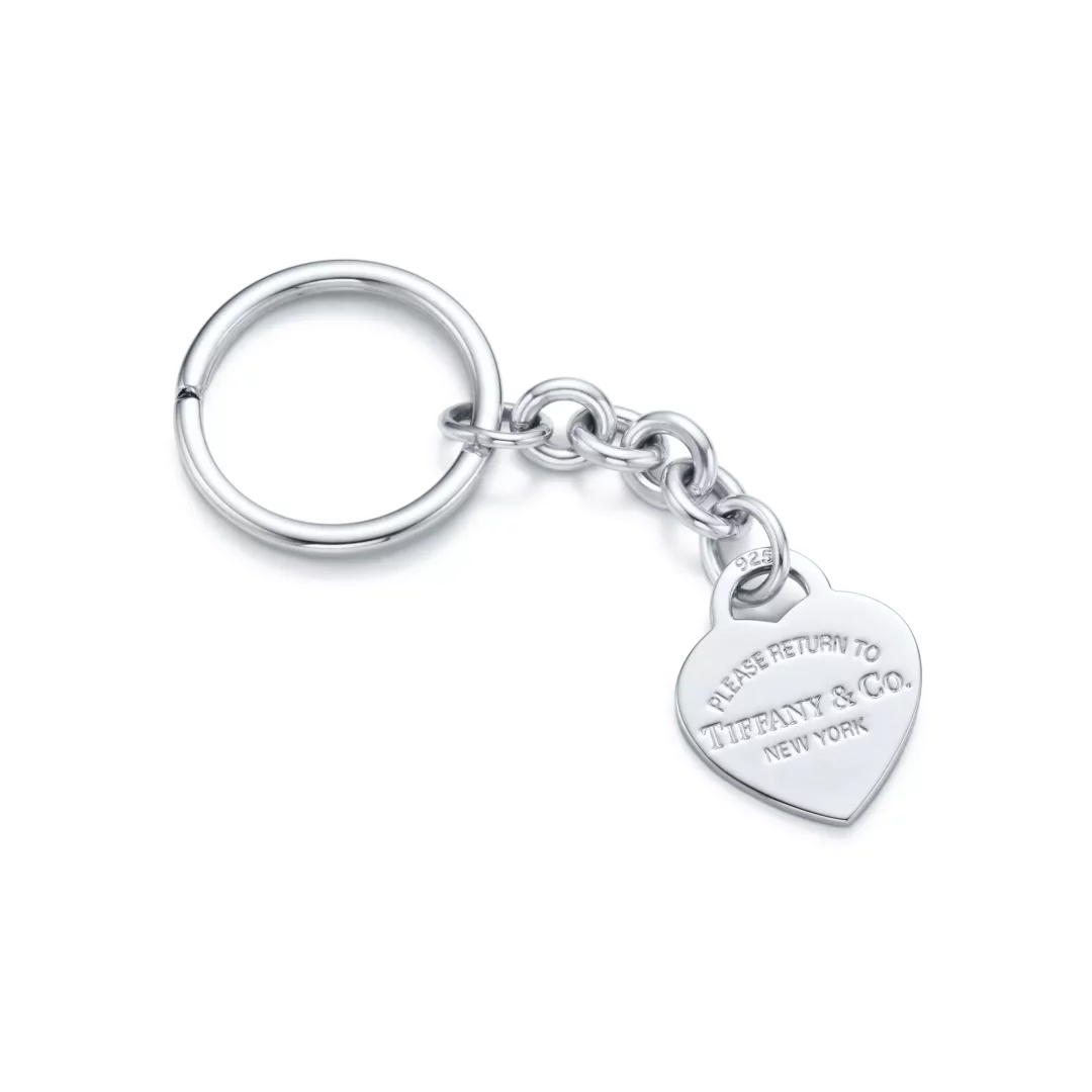 Büyük bir anahtar halkası, zincir bağlantıları ve üzerinde PLEASE RETURN TO TIFFANY & Co. NEW YORK yazısı ile 925 damgası bulunan parlak, kalp şeklinde bir charm'dan oluşan, Tiffany'nin ikonik Return to Tiffany koleksiyonundan zarif bir gümüş anahtarlık.