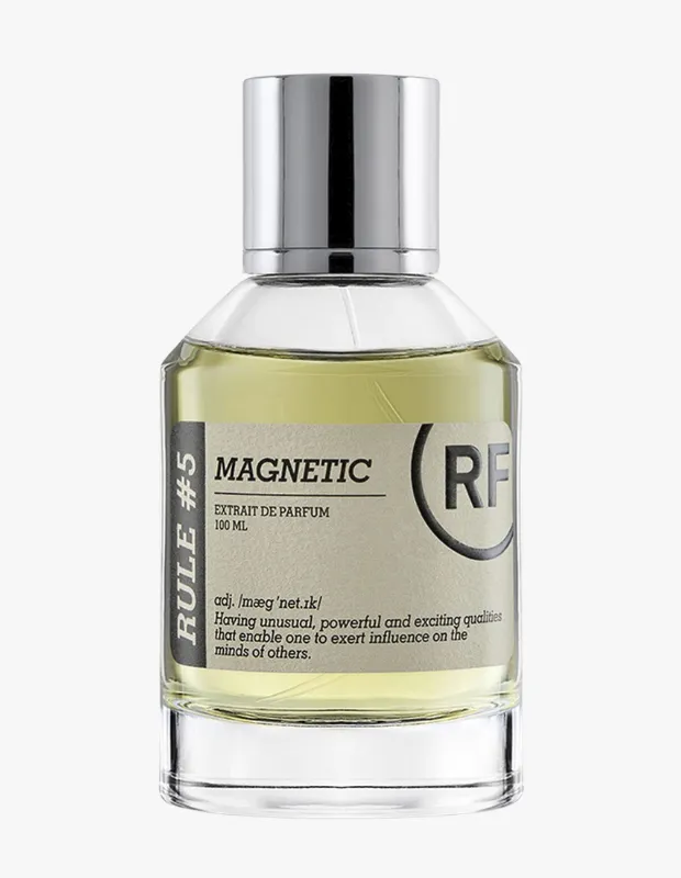 Gümüş kapaklı, şeffaf cam Rule Fragrances Rule #5 Magnetic Extrait de Parfum şişesi, açık sarı rengiyle dikkat çekiyor ve üzerinde Having unusual, powerful and exciting qualities that enable one to exert influence on the minds of others tanımı ile Magnetic ifadesi belirgin bir şekilde yer alıyor.
