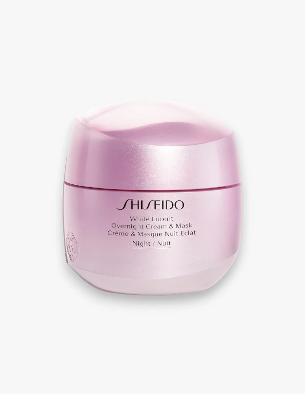 Beyaz bir arka plan üzerinde merkezi konumlandırılmış, inci pembesi ve lila yansımalı, dalgalı kapaklı Shiseido White Lucent Overnight Cream & Mask kavanozu, üzerinde marka ve ürün adı ile birlikte zarif kabartma detayıyla cildin gece boyu yenilenme ve ışıltılı görünüm kazanmasına yönelik bir ürün olarak dikkat çekiyor.