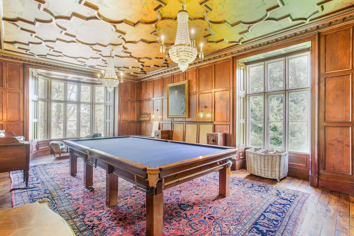Mavi keçeli bilardo masasının hakim olduğu bu lüks Stanley Park bilardo odası, ahşap panelli duvarlar, iki kristal avizeyle süslü oymalı tavan, bahçeye bakan geniş pencereler ve desenli, büyük bir halıyla döşenmiş, zengin detaylı tarihi bir mekanı gözler önüne seriyor.