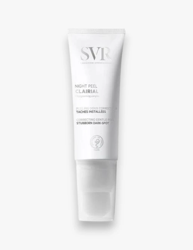 Beyaz bir zeminde duran, üzerinde büyük harflerle SVR logosu ve hemen altında NIGHT PEEL CLAIRIAL ibaresi yer alan, inatçı koyu lekelerin görünümünü azaltmaya yardımcı olan nazik bir düzeltici peeling ürününün beyaz ambalajlı tüpü.