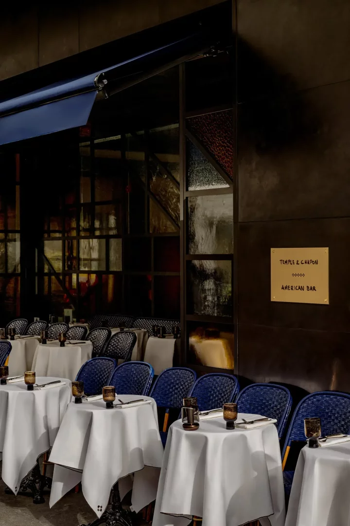 Koyu renkli cephesi, zengin detaylı vitray görünümlü cam panelleri ve Temple & Chapon American Bar tabelasıyla dışarıdan bile etkileyici bir ambiyans sunan restoranın ön kısmında, beyaz örtülü zarif masalar ve lacivert hasır sandalyeler Marais'de New York chophouse tarzında uzun bir akşam için misafirleri ağırlamaya hazır.