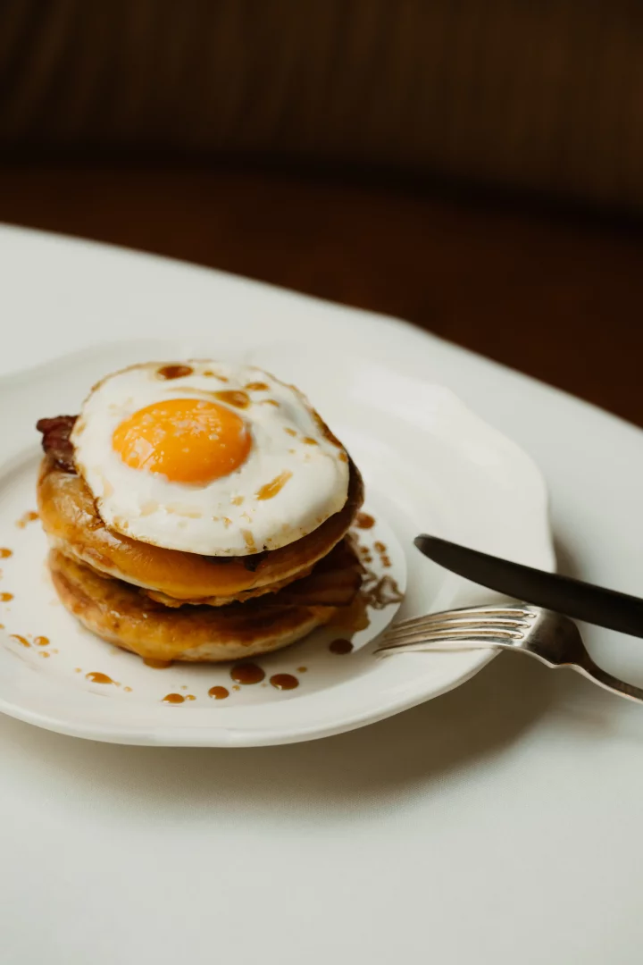 Beyaz bir tabakta, üzerine parlak sarı sarılı bir göz yumurta ve tatlı şurup gezdirilmiş kat kat pankek, Temple & Chapon'un New York chophouse kültüründen ilham alan hafta sonu brunch menüsünden davetkar bir örnek sunuyor.