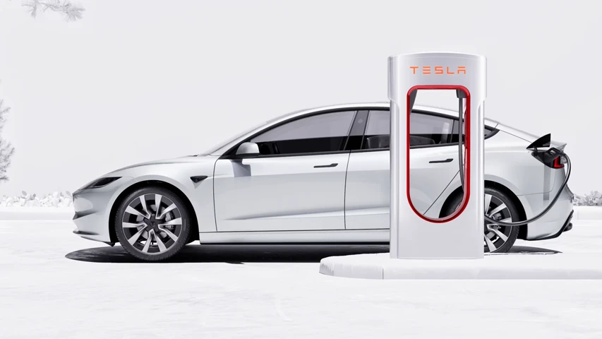 Minimalist bembeyaz bir ortamda, hafif karlı ağaçların yer aldığı fonda, arka kısmından Tesla Supercharger istasyonuna bağlı bir şekilde şarj olmakta olan zarif beyaz bir Tesla Model 3 elektrikli araç yan profilden gösteriliyor.
