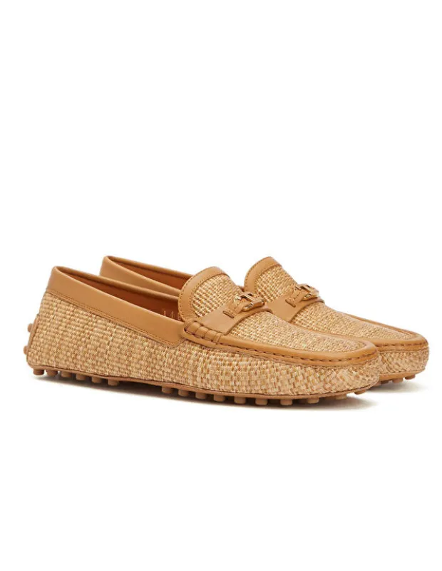 Tod's'un ikonik Gommino loafer ayakkabıları, bej rafya hasır dokulu gövdesi, taba rengi deri detayları ve markanın imzası haline gelen karakteristik kauçuk tabanlarıyla sessiz lüks estetiğini zarifçe yansıtıyor.