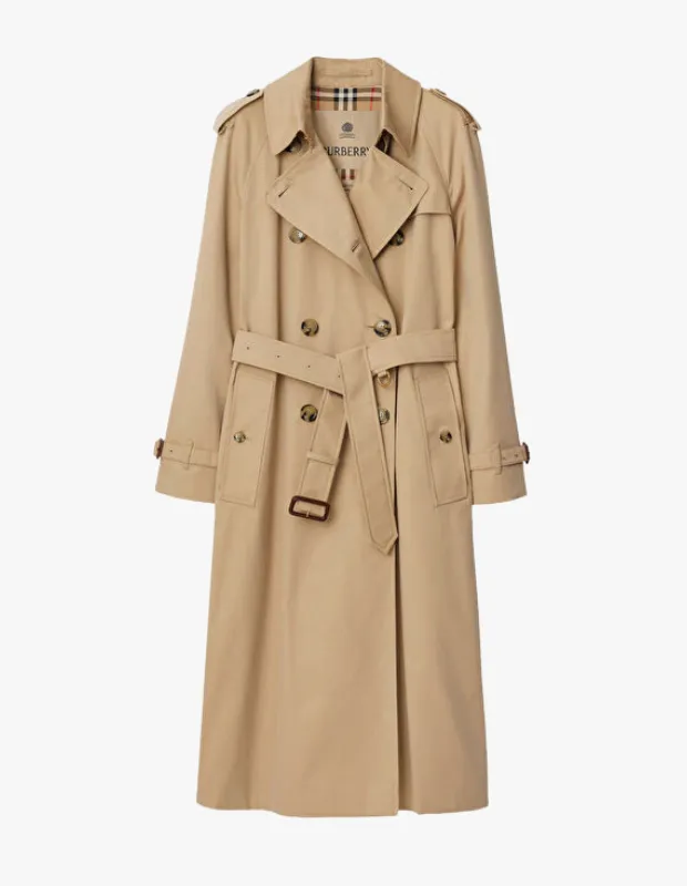 Beyaz arka plan üzerinde tüm detaylarıyla sergilenen, klasik bir trençkot olan bu bej renkli çift düğmeli palto, Burberry'nin ikonik ekoseli astarını ve omuzdaki apoletleri gösteren belden bağlamalı zarif bir tasarıma sahiptir.