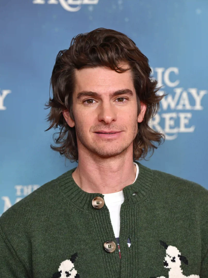 Yeşil, örgü bir hırka giymiş ve hafif dalgalı, kahverengi uzun saçlarıyla objektife bakan Andrew Garfield'ın bu portresi, uzun erkek saç modelleri arasında doğal ve bakımlı bir stilin mükemmel bir örneğini sergiliyor.