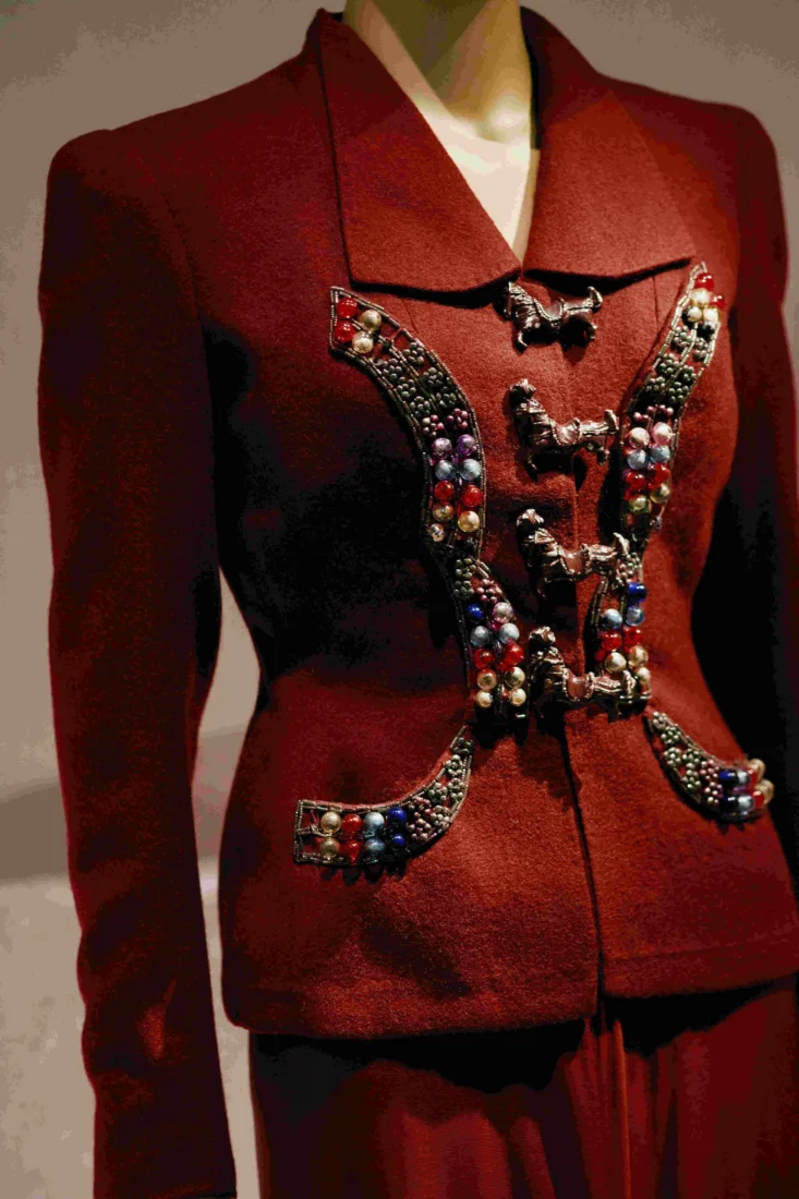 Ciddi bir ifadeye sahip model, omuzlarında dikkat çekici altın rengi heykelsi detaylar içeren eşsiz bir Schiaparelli haute couture üst giysisiyle sahne arkasında durarak, markanın yaratıcı atmosferinden bir kesit sunuyor.