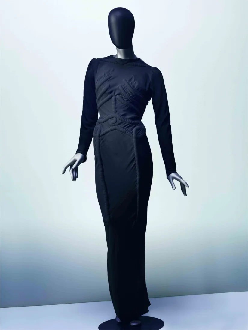 Elsa Schiaparelli'nin çığır açan tasarımlarından biri olan, insan iskeletinin anatomik detaylarını kabartma dikişlerle zarifçe işlenmiş, uzun ve ikonik iskelet elbisesi, moda tarihinde sürrealist estetiğin çarpıcı bir örneğini sunar.
