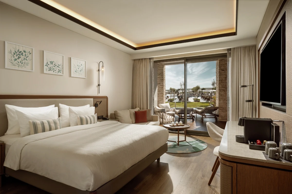 Anda Barut Collection otelinin ferah, modern ve doğrudan havuza ve deniz manzarasına açılan terası olan Deluxe Aile Süiti'nde, bembeyaz çarşaflı konforlu bir yatak, duvarda asılı botanik tablolar, şık bir oturma grubu ve çalışma masası yer alıyor.