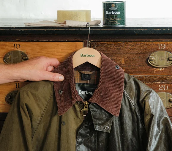 Koyu renkli, klasik kesimli, kadife yakalı ve belirgin ceplere sahip bir Barbour wax ceket, markanın 132 yıllık köklü mirasını ve yalnızca bir giysi değil, nesilden nesile aktarılabilen, onarılabilir ve sahibinin hayatına karışan zamansız bir yol arkadaşı olma özelliğini görselleştiriyor.
