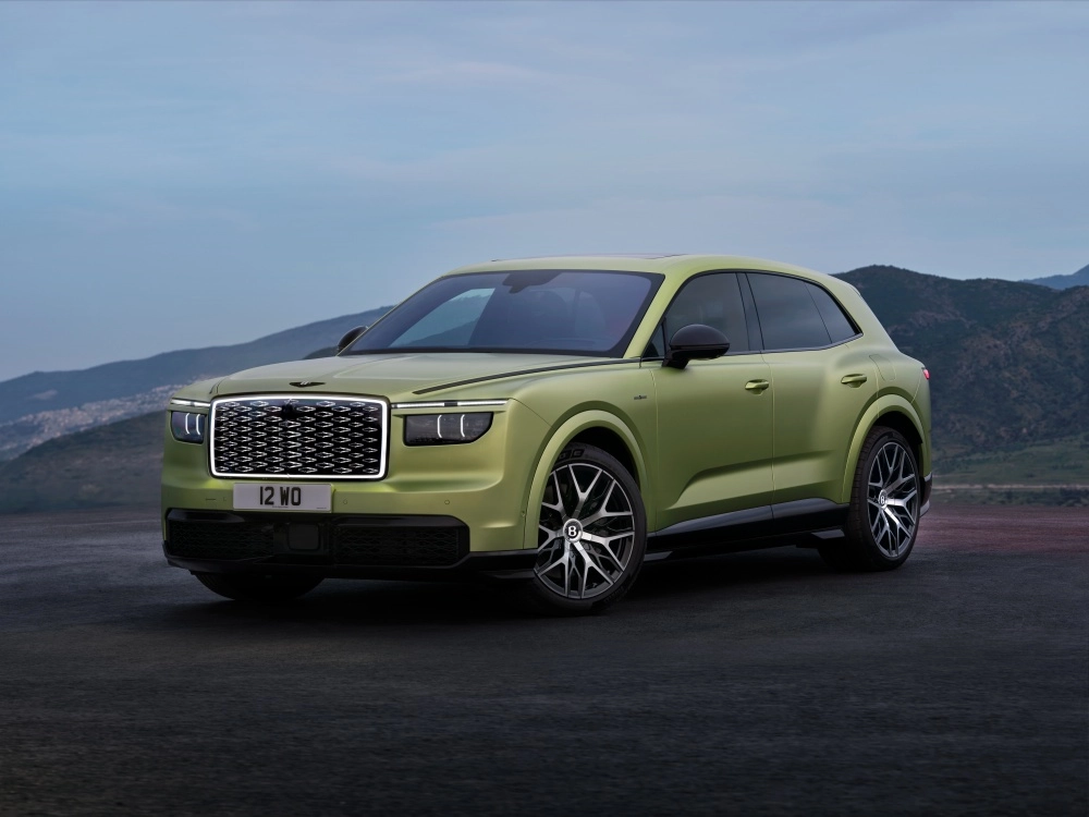 Parlak yeşil metalik renkteki lüks ve sportif Bentley Torcal elektrikli SUV, modern tasarım çizgileriyle öne çıkan ön sol profilini aydınlık bir showroomda sergileyerek markanın geleceğe dönük elektrikli araç vizyonunu çarpıcı bir şekilde yansıtıyor.