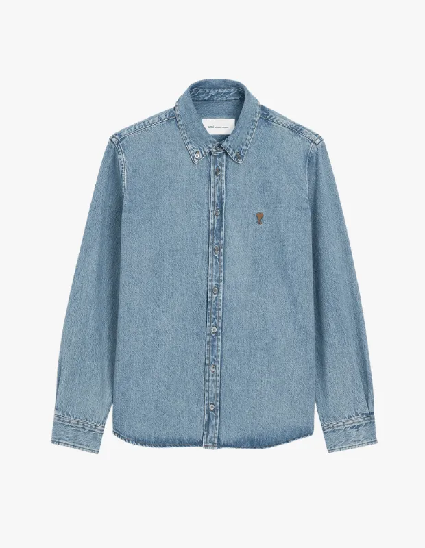 Açık mavi kot kumaşından yapılmış, uzun kollu, düğmeli yakalı ve sol göğsünde küçük kahverengi bir logo işlemeli bu gömlek, blazer kombileri ve rahat sokak stili için mükemmel bir seçenek sunuyor.