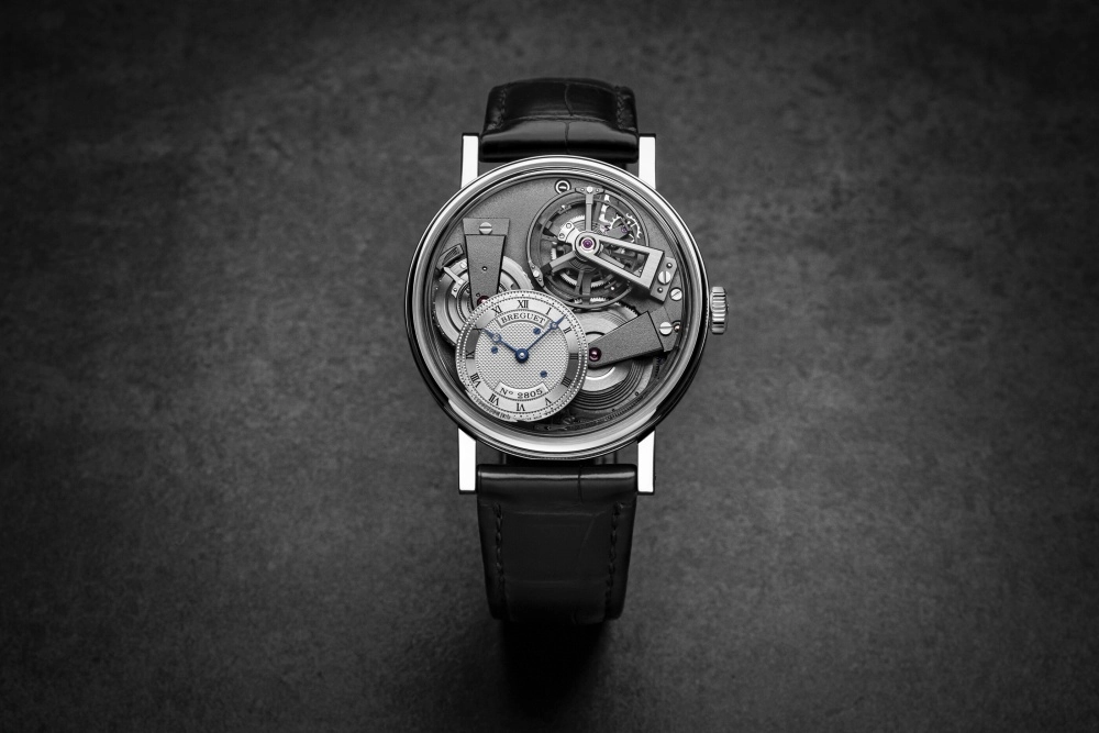 Breguet Tradition Tourbillon 7047 saatinin büyüleyici yakın çekim görüntüsü, karmaşık iskeletleştirilmiş mekanizmasını, ustalıkla yerleştirilmiş büyük tourbillonunu ve zarif dişli çarklarını gözler önüne sererek, yüksek saatçilik mühendisliğinin estetik bir şaheserini sergiliyor.