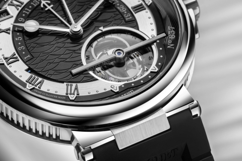 Breguet Marine Tourbillon Equation Marchante 5887 modelinin yakından çekilmiş bu fotoğrafında, parlak rose gold kasası, okyanus dalgası desenli mavi kadranı, göz alıcı tourbillon mekanizması ve hassas denkleşen zaman göstergesi gibi üstün özellikler belirgin bir şekilde sergileniyor.