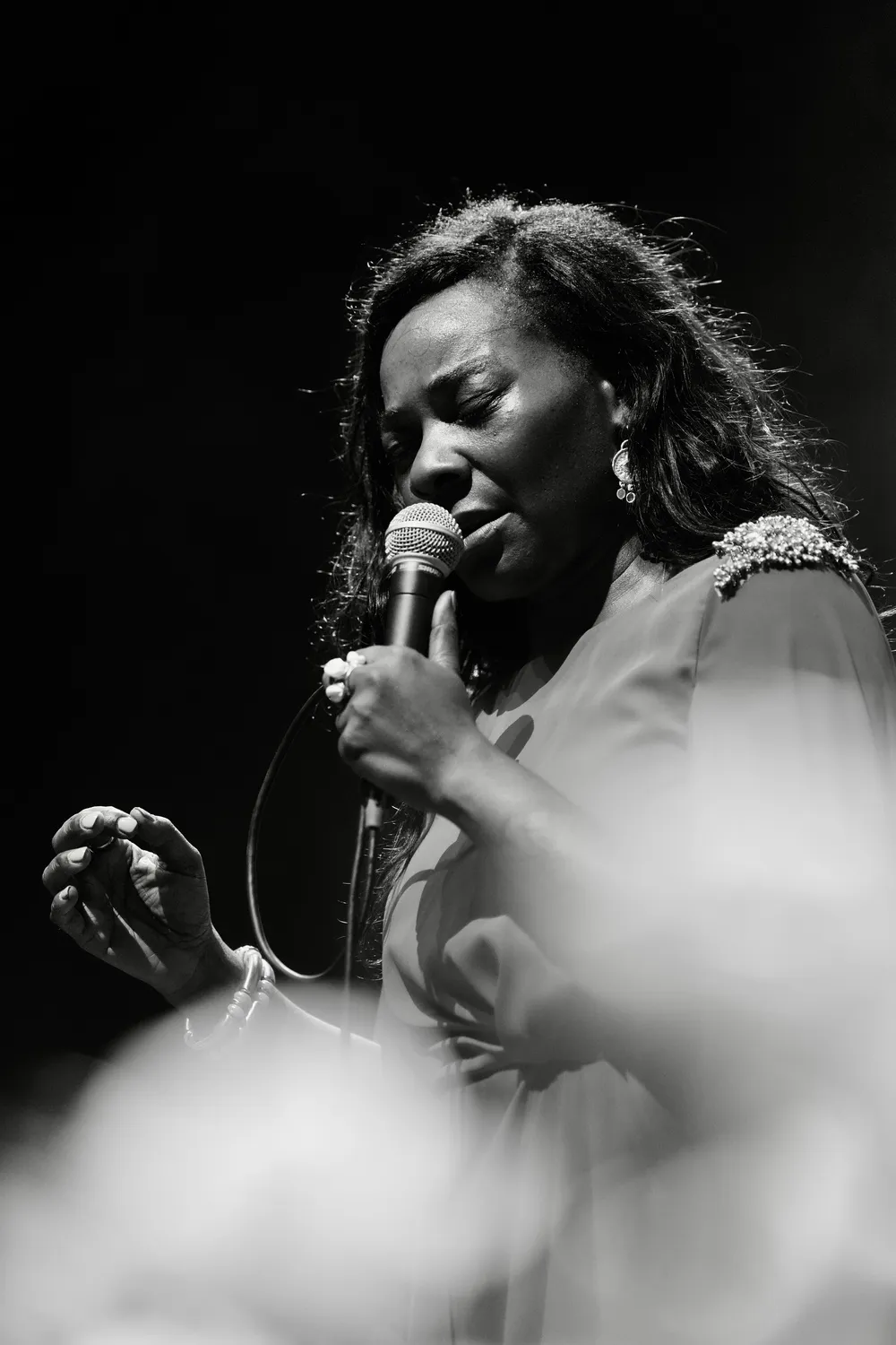 Buika, bir caz festivali kapsamında verdiği röportaj sırasında, siyah parlak kostümü ve karakteristik bukleli saçlarıyla canlı ve derin ifadesiyle objektife yansıyor, sanatsal duruşuyla merak uyandırıyor.