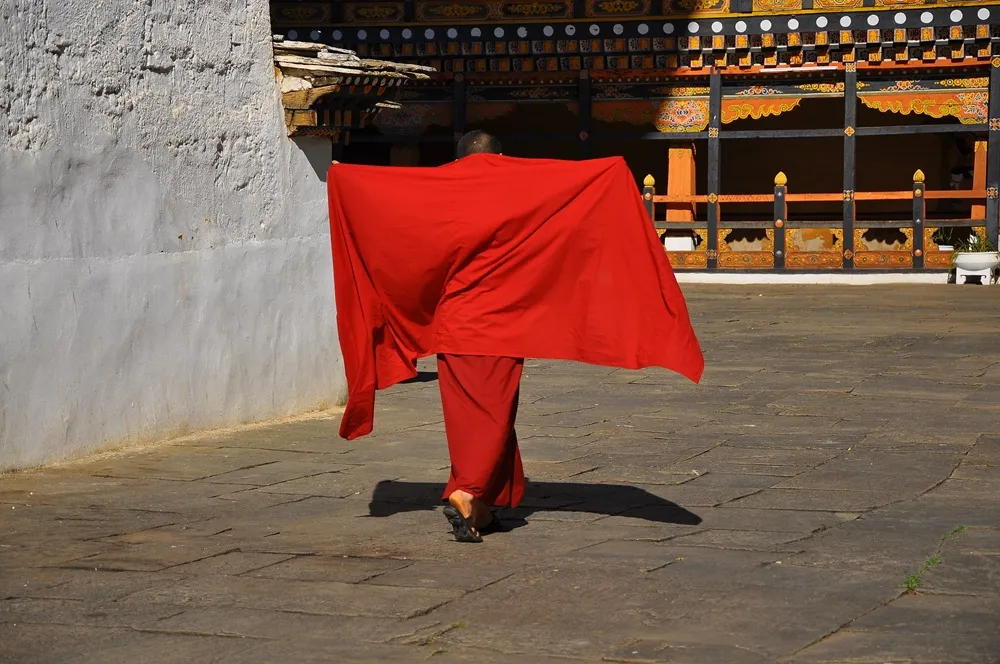 Butan'ın Himalaya eteklerinde, yemyeşil ormanlarla çevrili, geleneksel ahşap detaylara sahip, beyaz badanalı ve kırmızı çatılı görkemli bir manastırın veya dzong'un nefes kesen manzarası, ülkenin mistik atmosferini ve zengin kültürel mirasını gözler önüne seriyor.