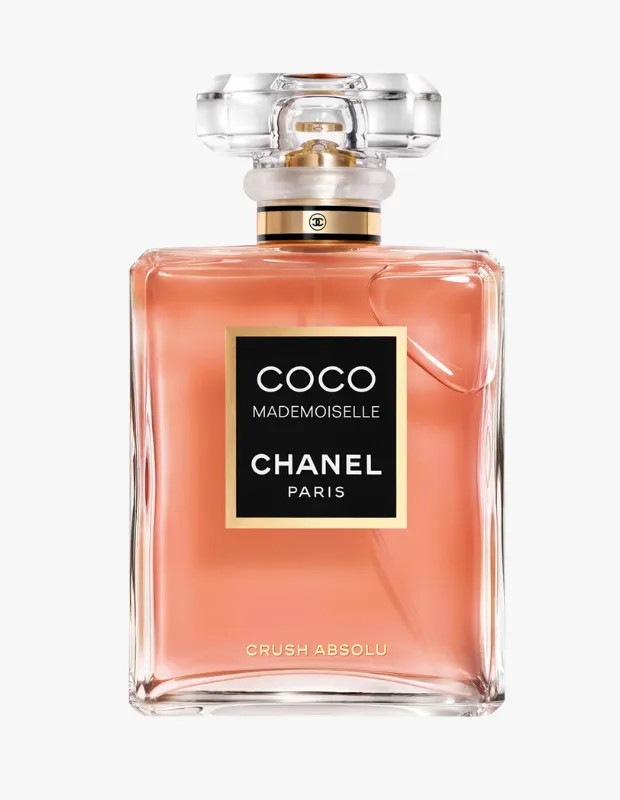Beyaz bir fon üzerinde sergilenen, zarif dikdörtgen şeffaf cam şişesi içinde şeftali rengi likit parfüm bulunduran, altın detaylı fasetli kapağı ve siyah etiketinde COCO MADEMOISELLE CHANEL PARIS yazılı ikonik Chanel Coco Mademoiselle Crush Absolu parfüm şişesi.